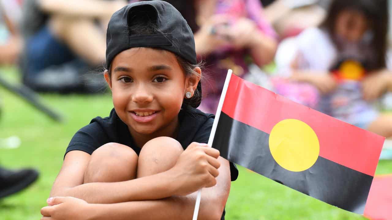 A child with an Aboriginal flag at an Invasion Day rally in Brisbane.