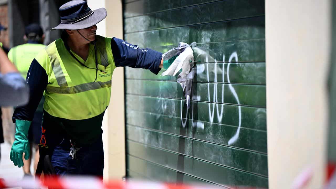 A council worker cleans anti-Semitic graffiti from a garage door.