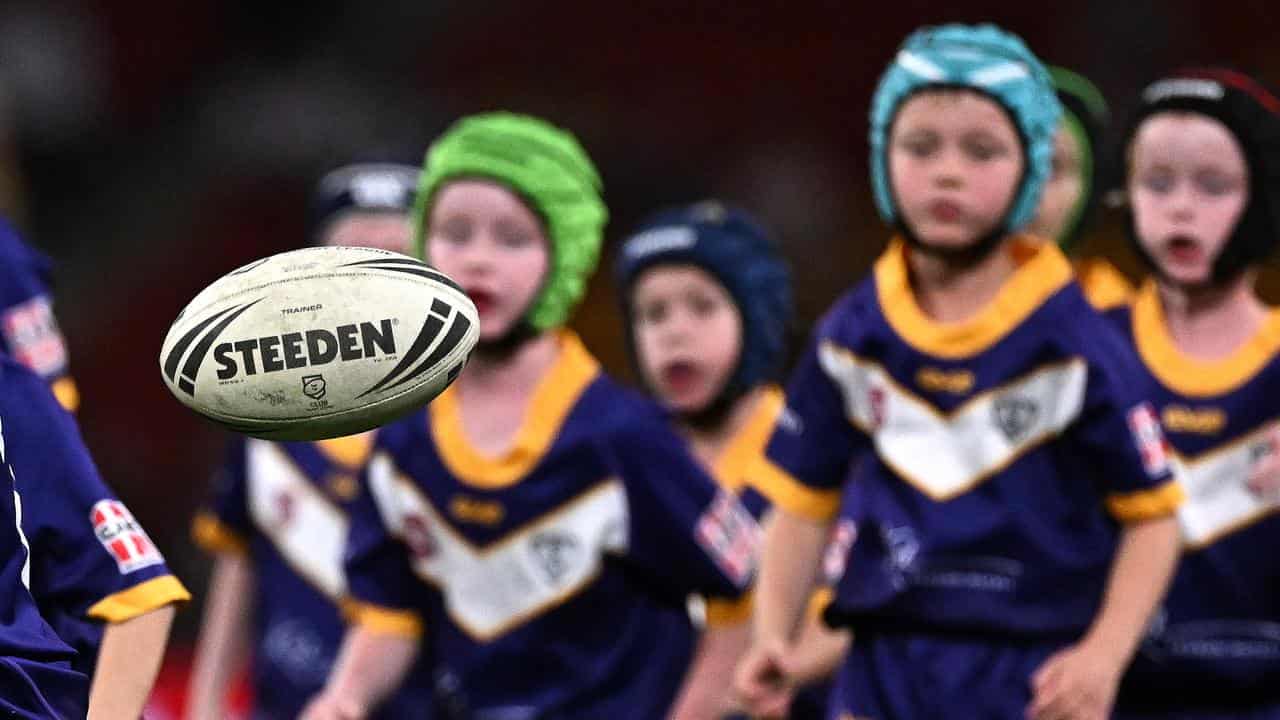 Children in safety headwear chase after a ball