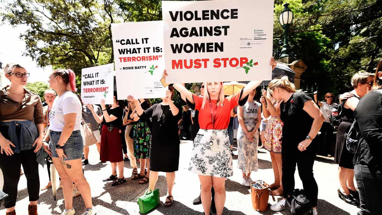 Protesters hold placards during a domestic violence protest