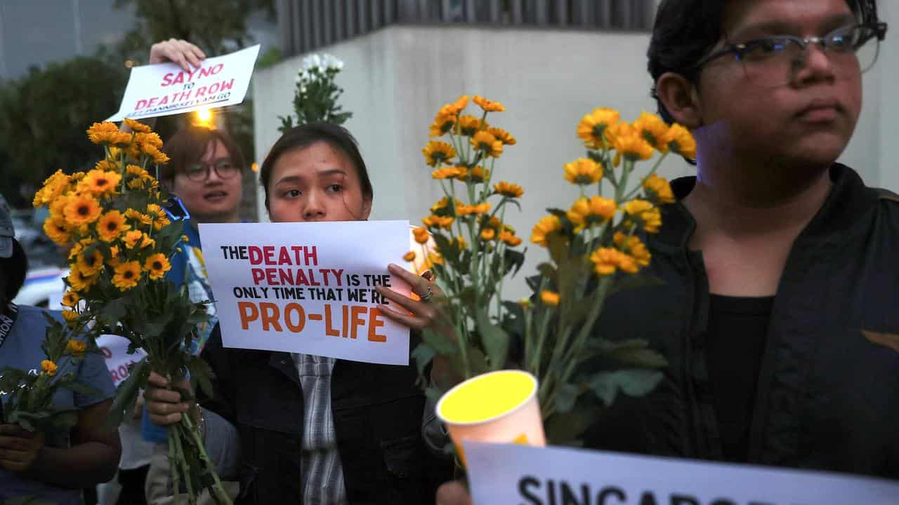 Human rights activists hold flowers, placards and candles 