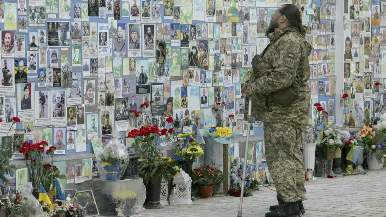 A serviceman mourns at a memorial in Ukraine