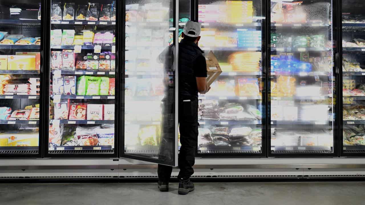 A man stacks a cold storage cabinet at a supermarket