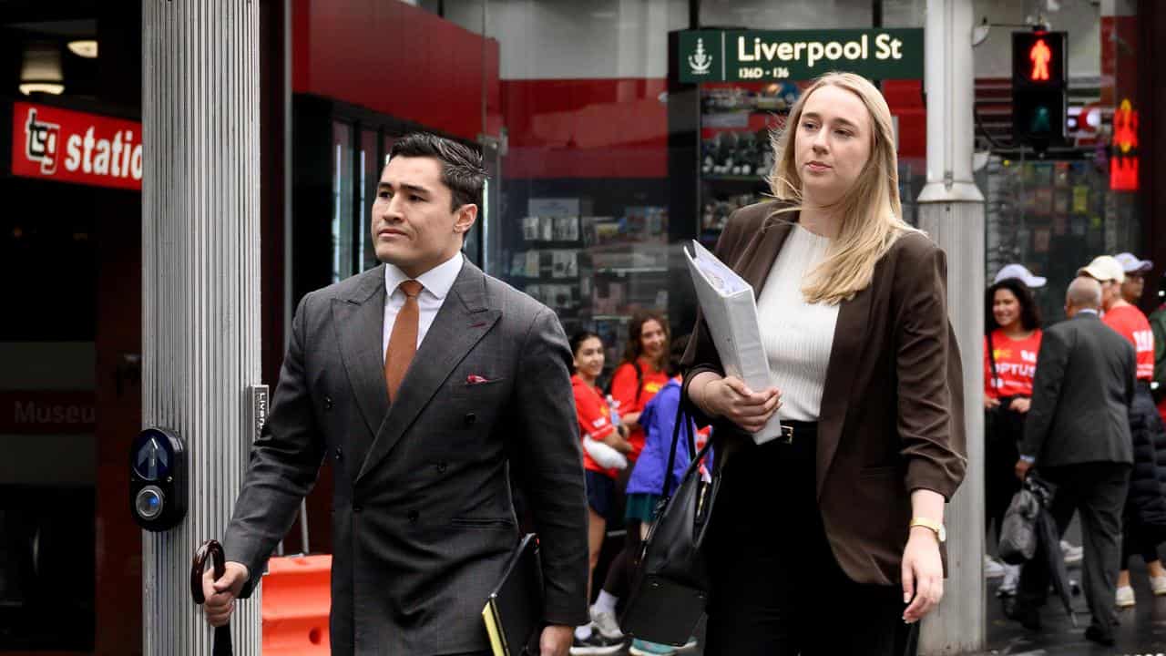 A man and a woman in business wear walk across a road