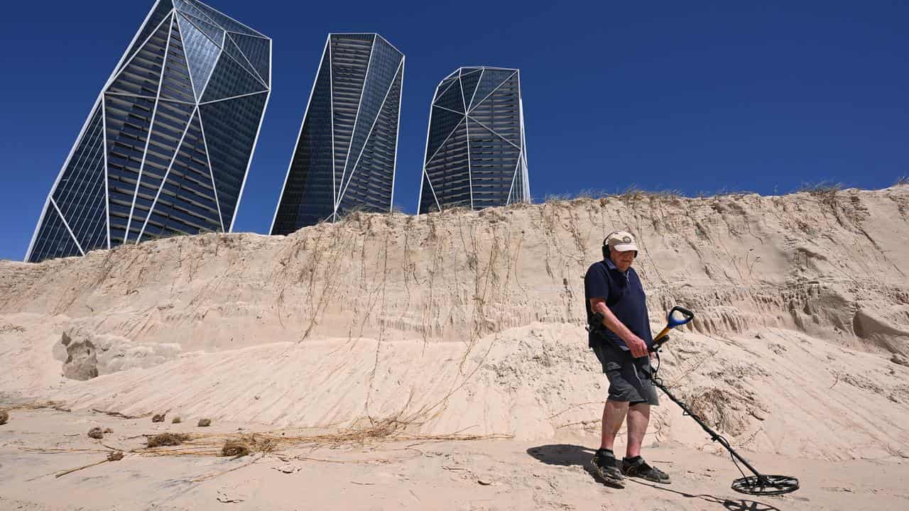 Metal detectorist Joe Goc searches for coins at Broadbeach.