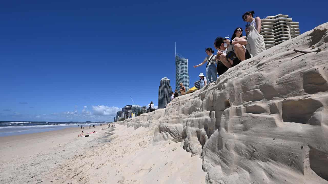 Japanese tourists view beach erosion at Surfers Paradise.