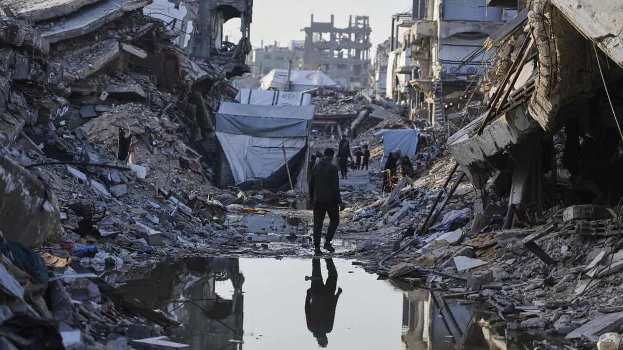 Palestinians walk amid the rubble