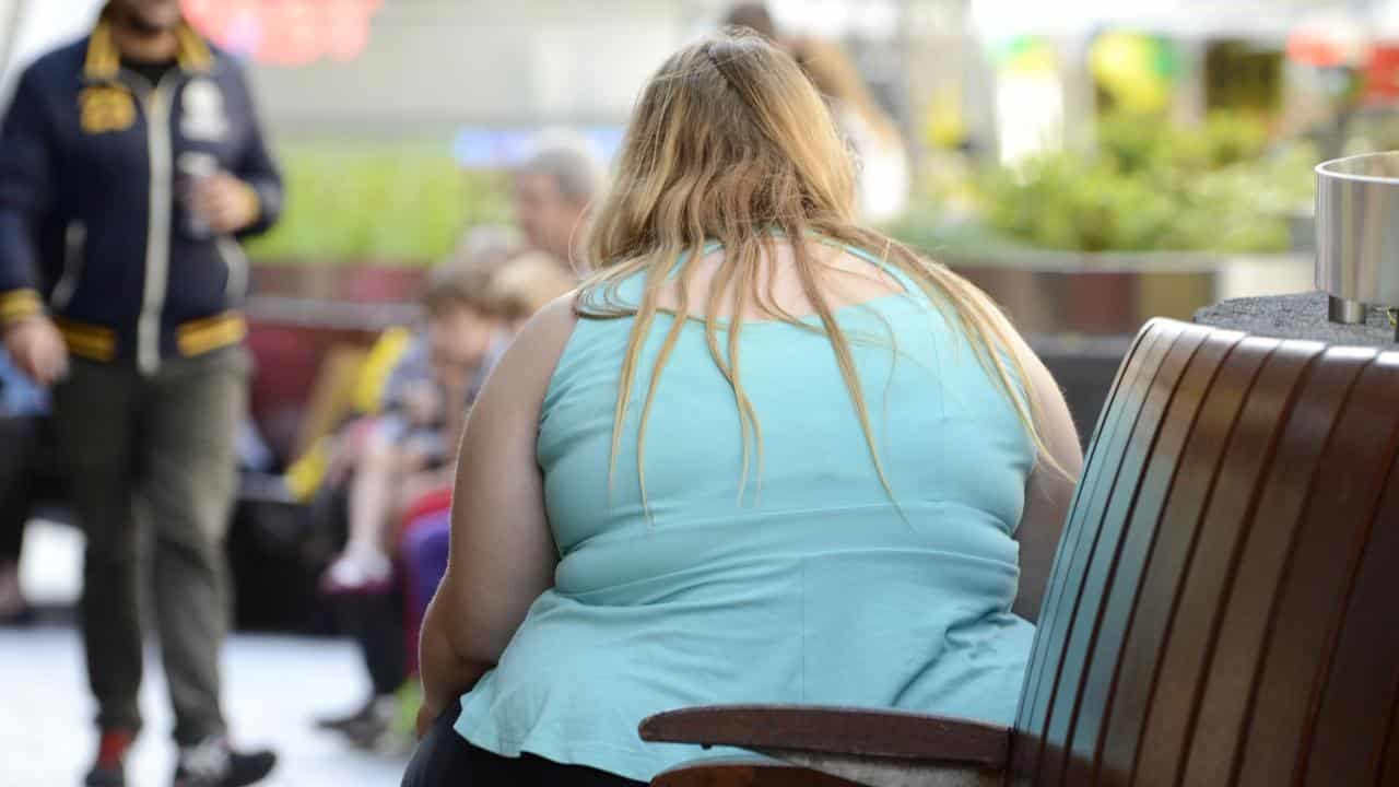 An obese woman on a street bench.