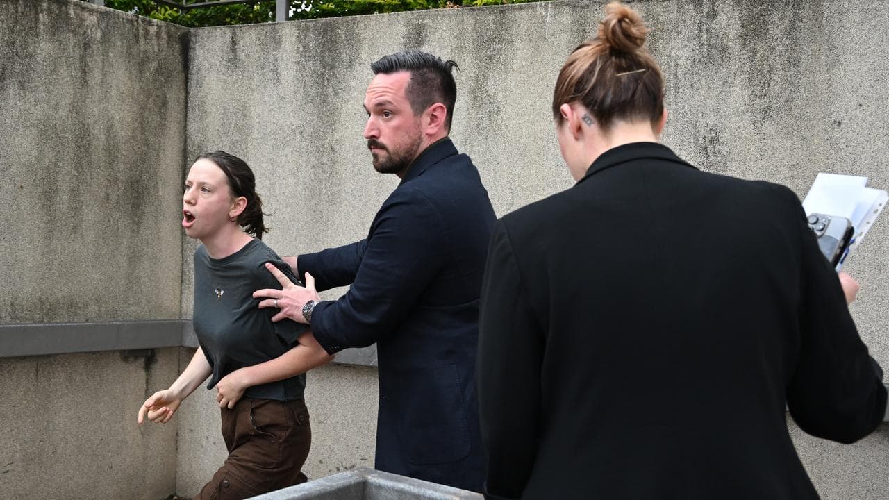 A protester is escorted away from Anthony Albanese's press conference