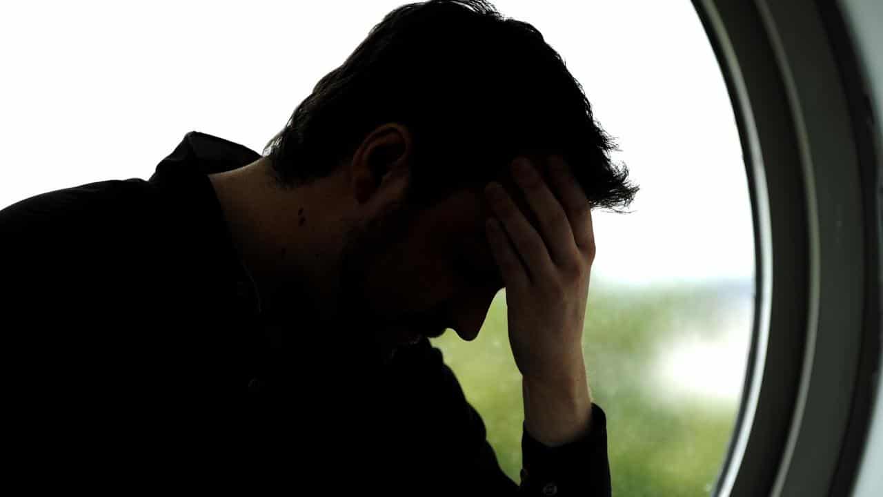 Stressed person holds head in hand