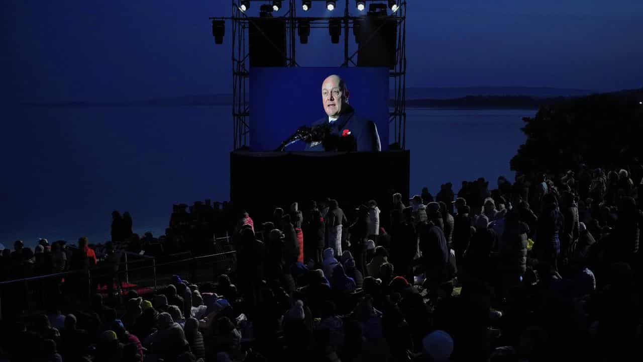 NZ Prime Minster Chris Luxon on a screen at Anzac Cove beach