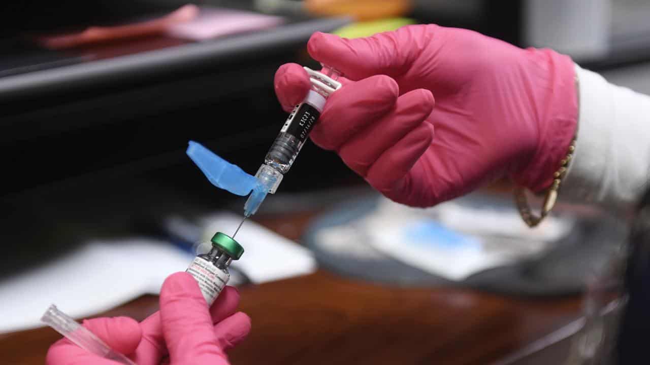 A health worker prepares an MMR shot.