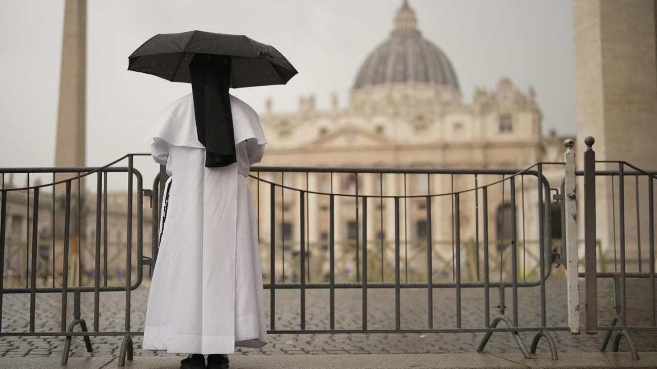 A nun shelters from rain as she follows a mass in St Peter's Basilica