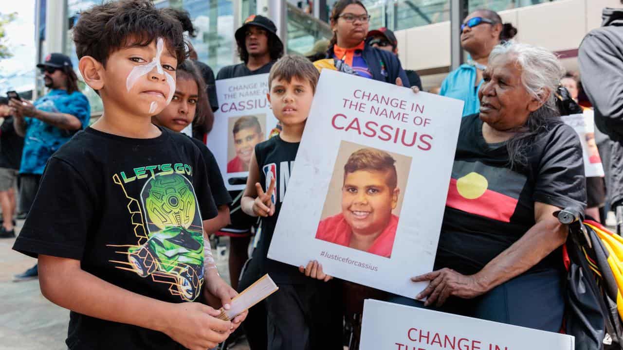 People hold signs showing Cassius Turvey at a rally in Perth
