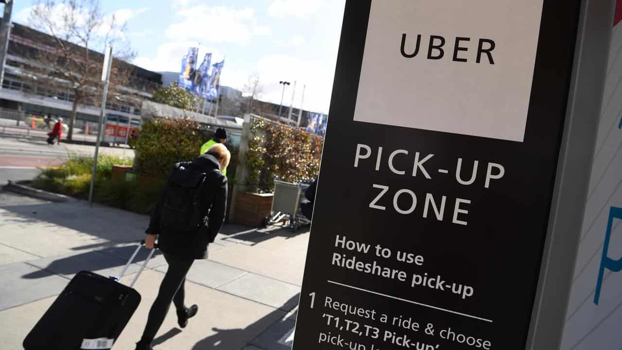 Travellers at an Uber pick-up zone outside an airport