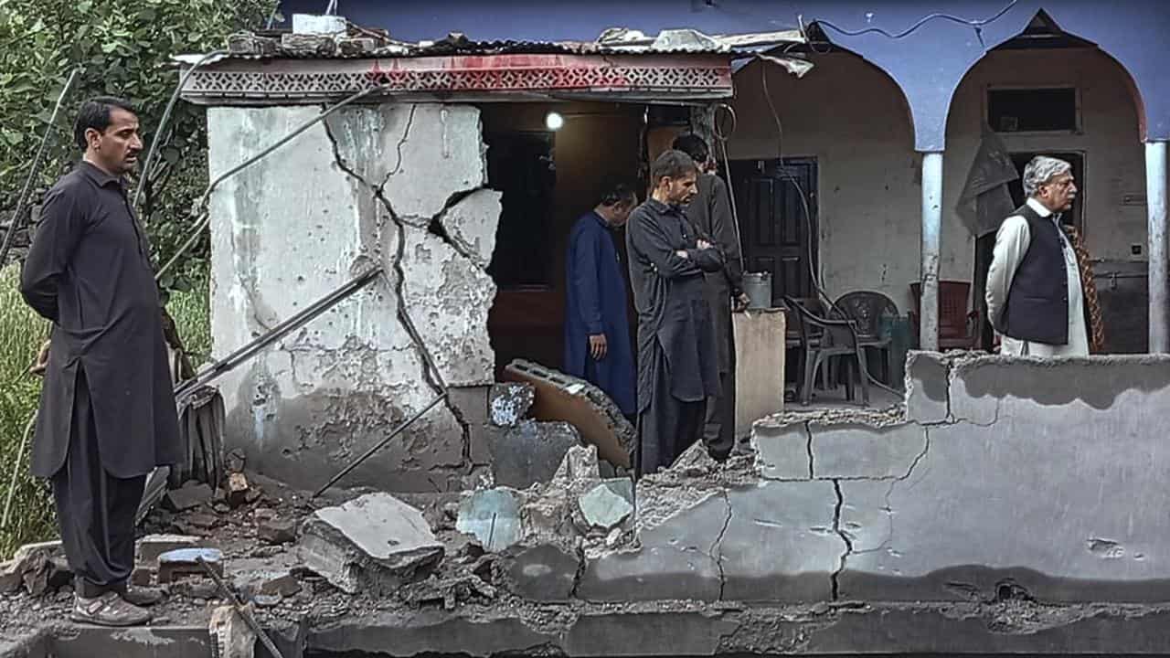 Residents examine their damaged house in Pakistani Kashmir