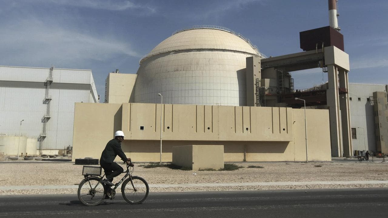 A worker rides a bicycle in front of a nuclear reactor