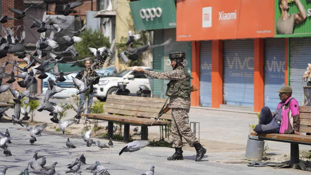 Indian soldier feeds pigeons at a market in Srinagar in Indian Kashmir
