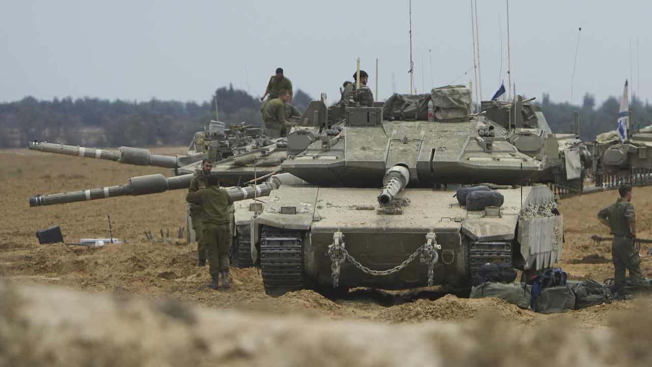 Israeli soldiers work on tanks near the border with the Gaza Strip