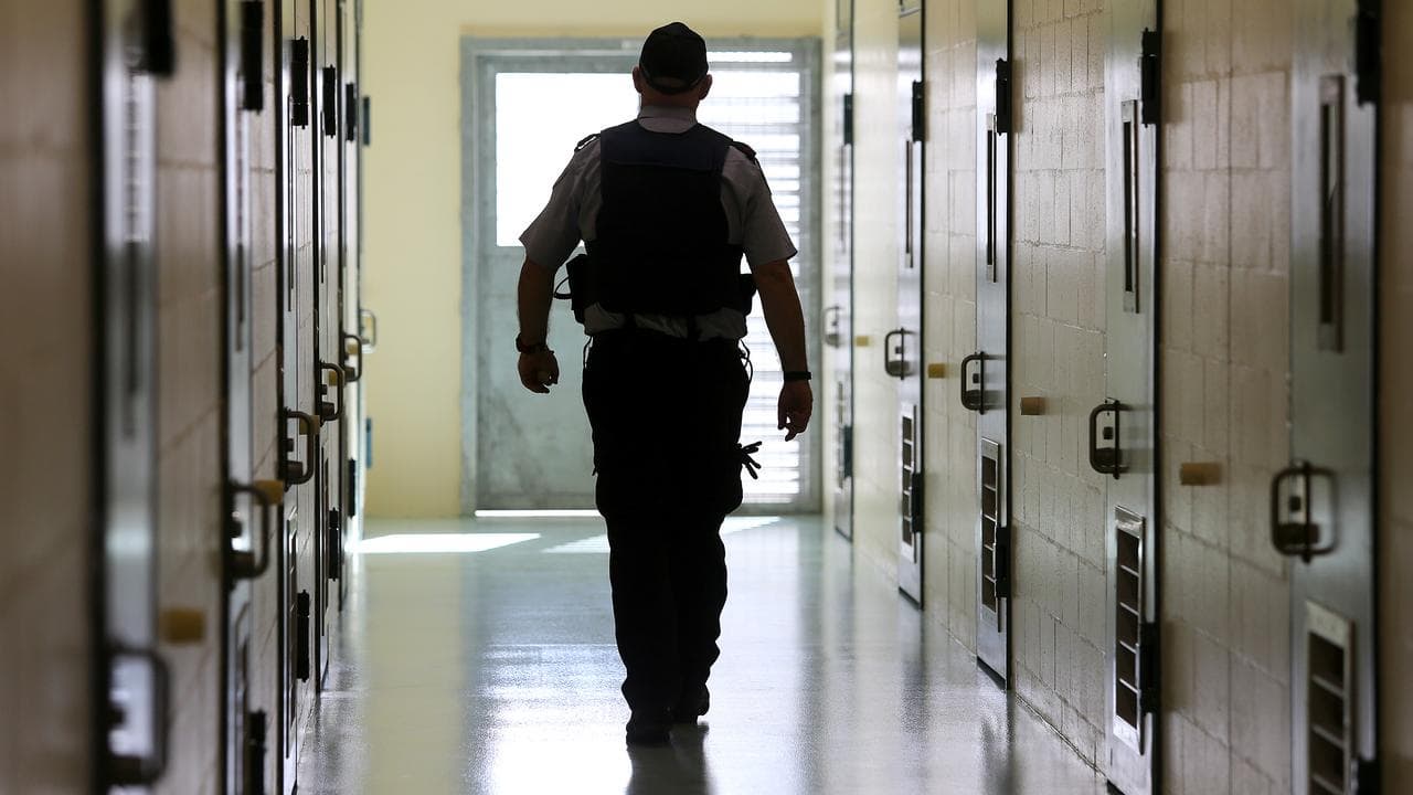 A corrections officer in a cell corridor