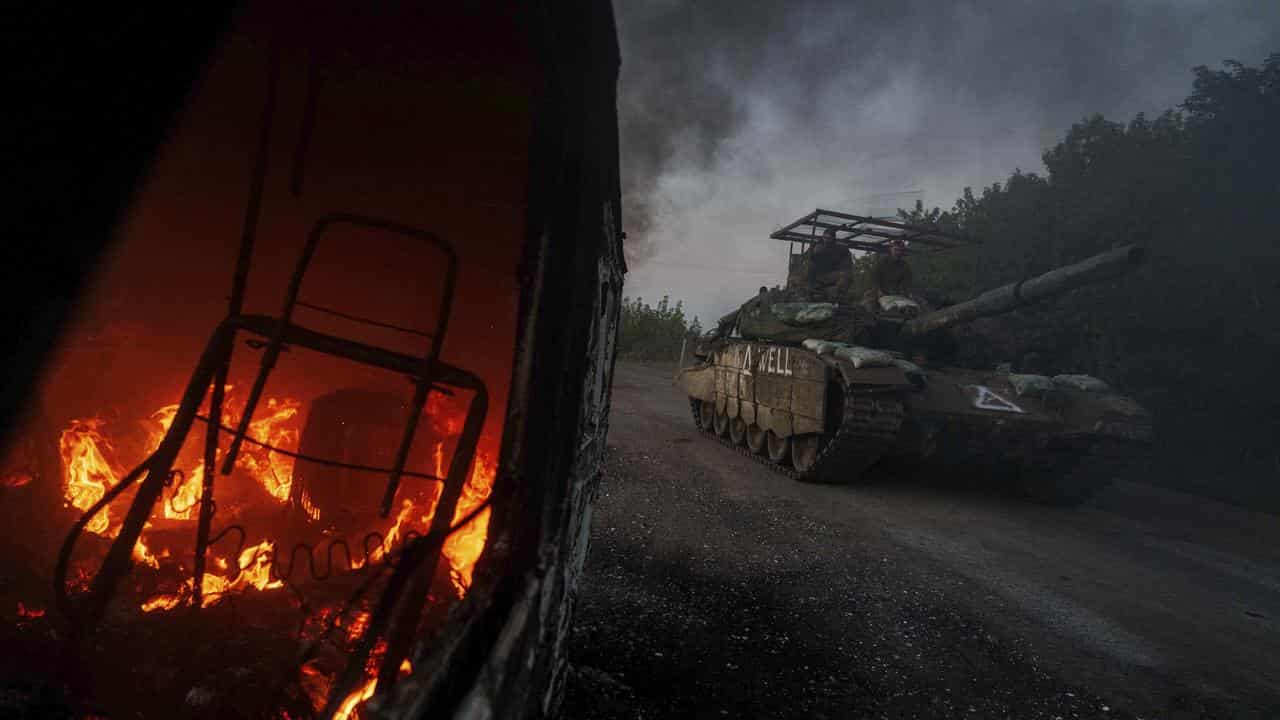 Ukrainian tank passes a burning car near the Russian-Ukrainian border