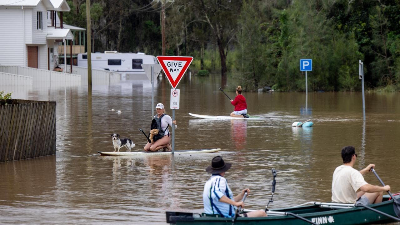 Residents on paddle boards and kayaks in floodwaters.