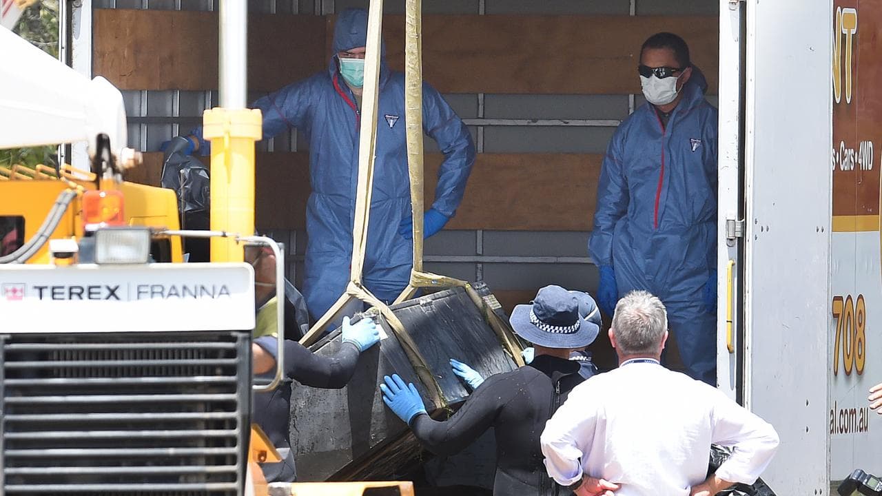 Police use a crane to load a metal box onto a truck (file image)