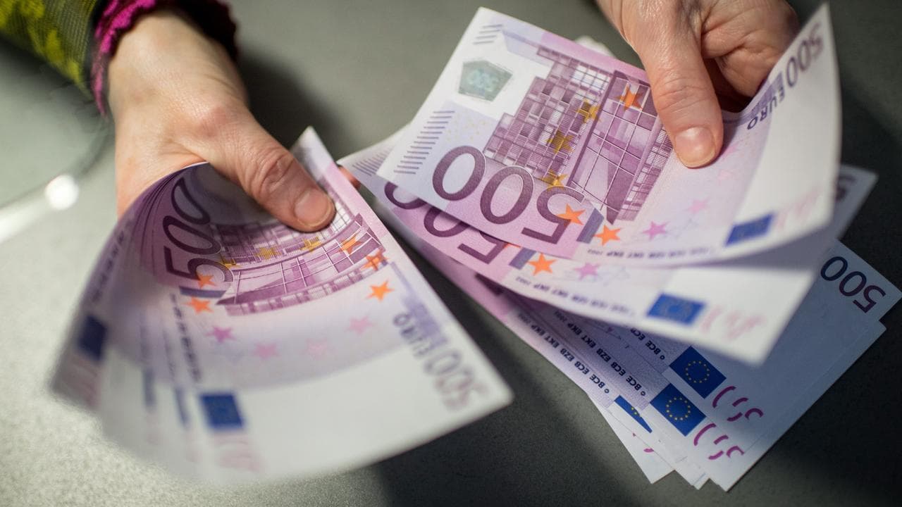 A person holding 500 euro notes.