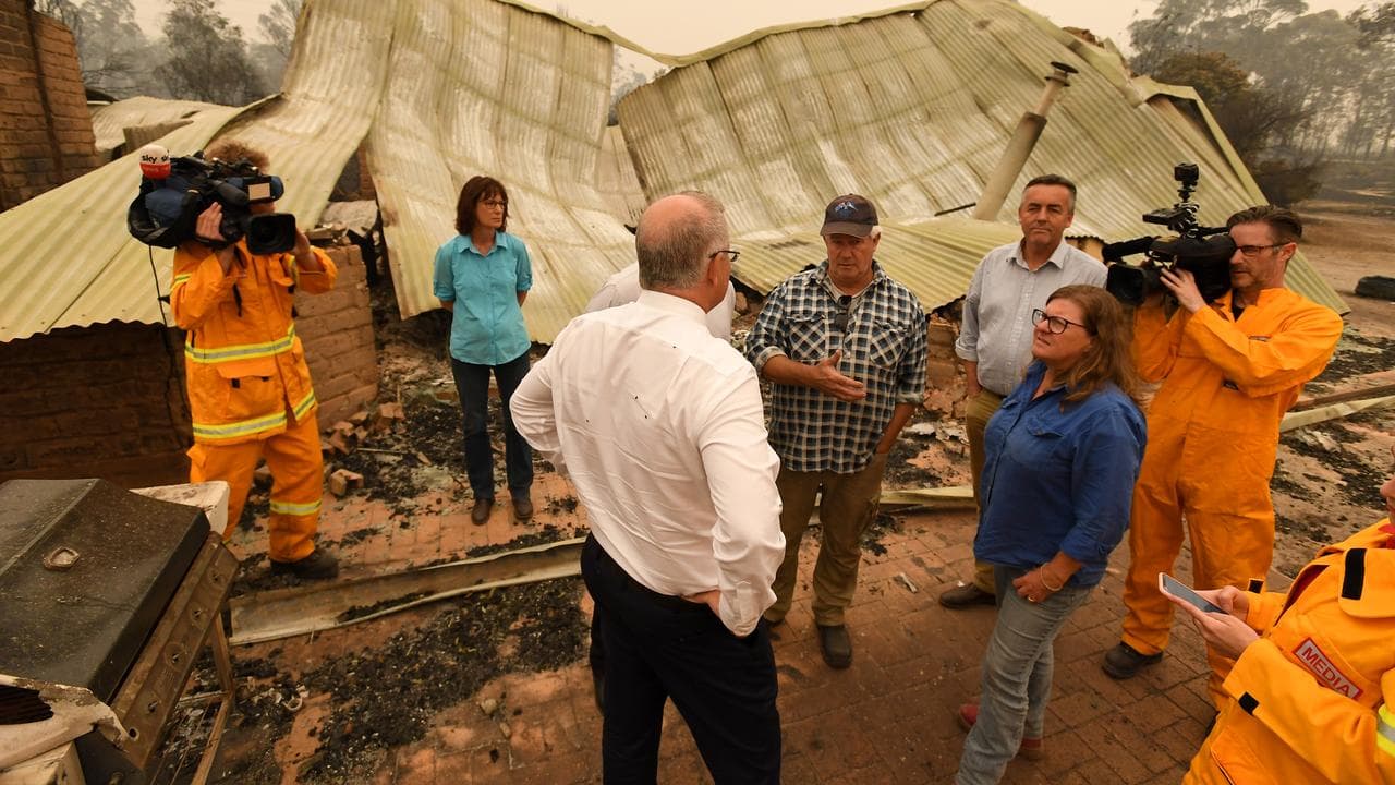 Scott Morrison talking to people beside a property destroyed by fire.
