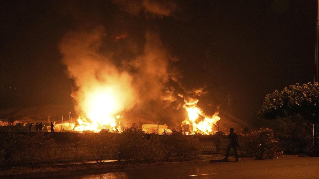 People watch as flames rise from an oil storage facility
