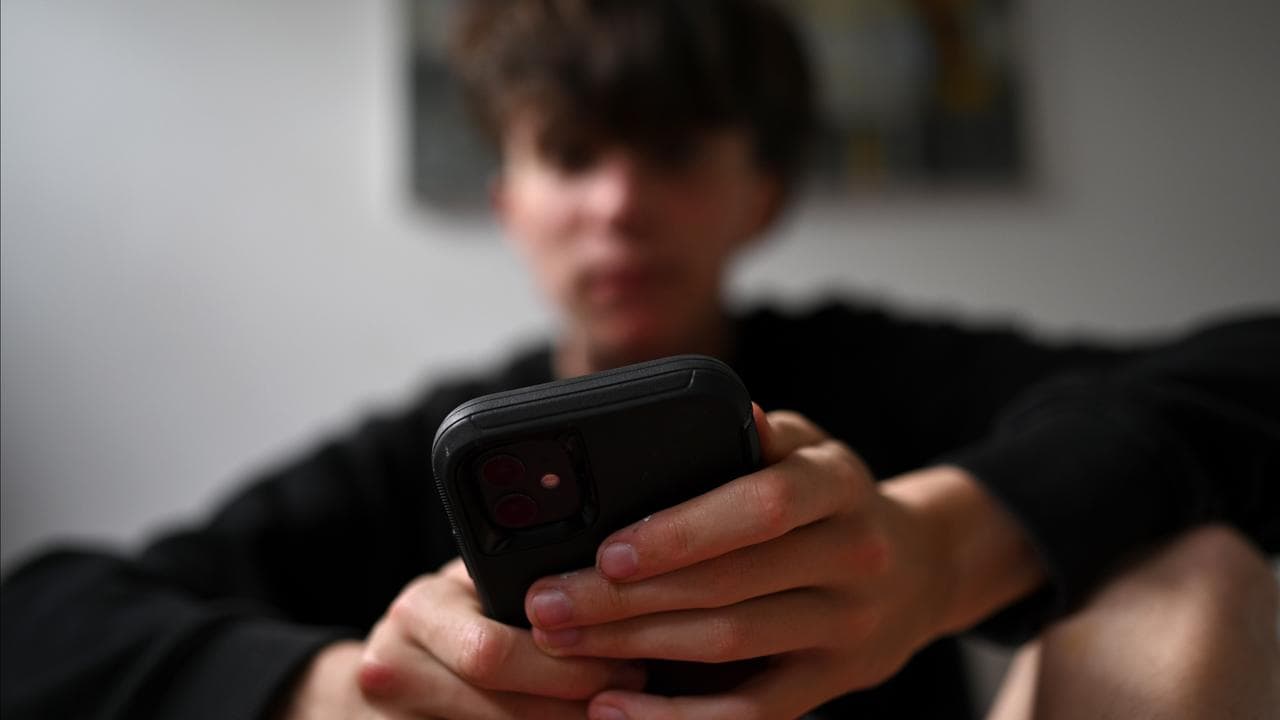 A teenager uses his mobile phone to access social media
