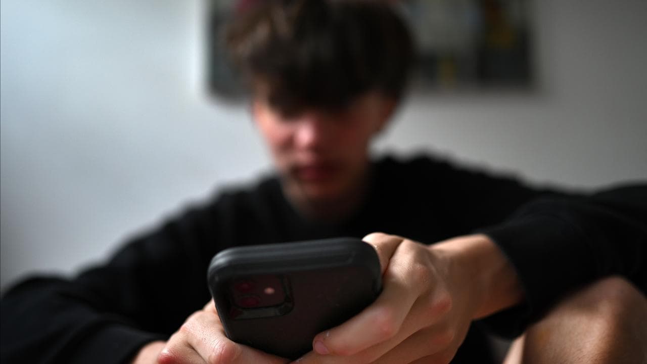 A teenager uses his mobile phone to access social media