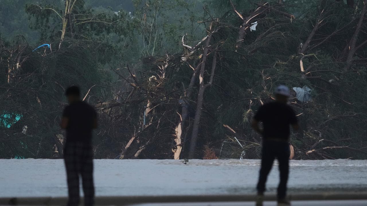 Onlookers survey damage caused along the Guadalupe River