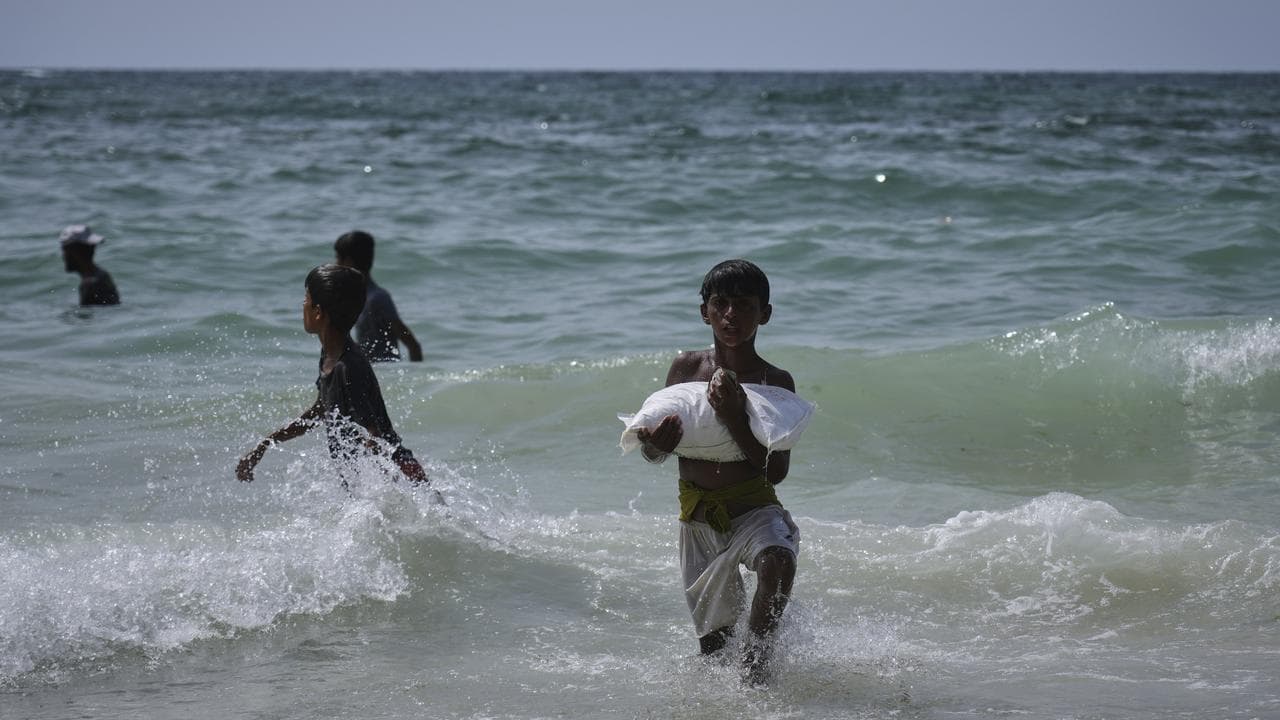 A youth carries a sack of aid that landed in the Mediterranean Sea