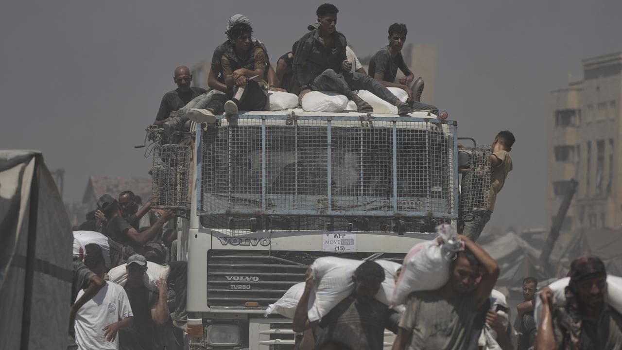 Palestinians carry flour unloaded from an aid convoy in Gaza City