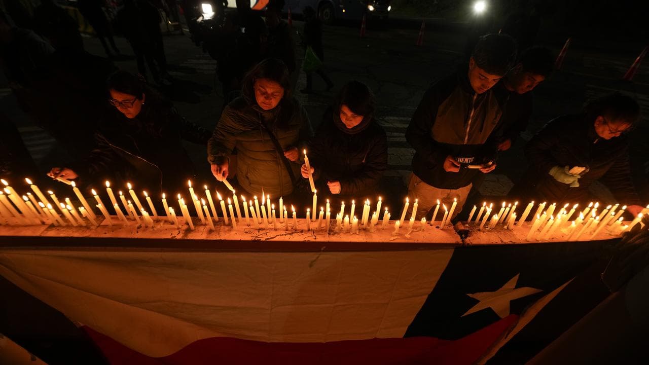 People light candles at a vigil in front of El Teniente copper mine