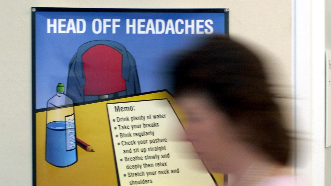 Woman walks past headache prevention poster