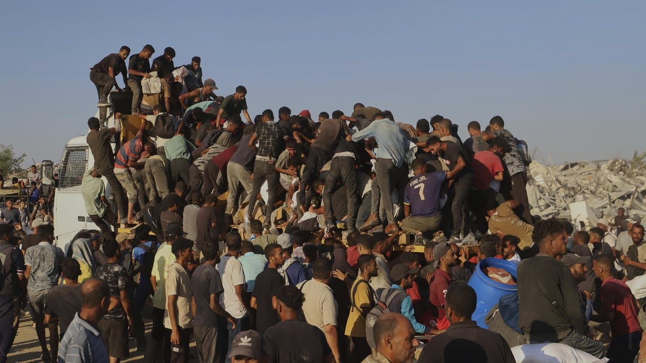 Palestinians ride on a truck loaded with food