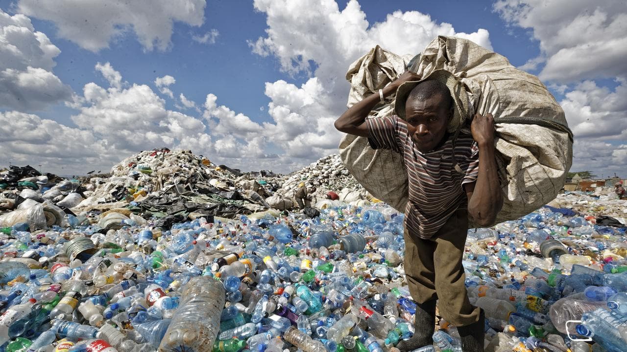 A man walks on a mountain of plastic bottles