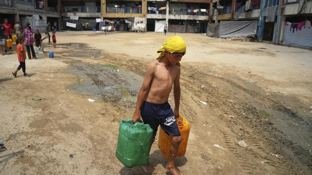Boy carries jerrycans after collecting water in Gaza City