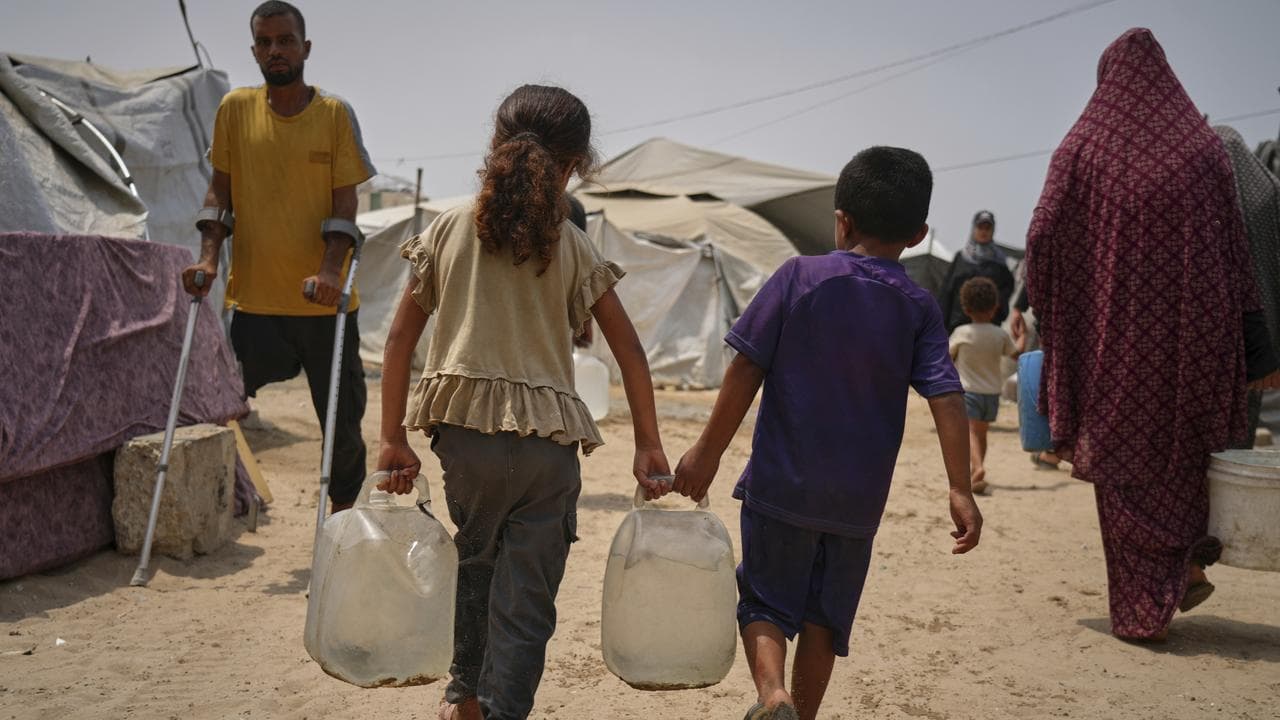 Palestinian displaced children haul jerrycans
