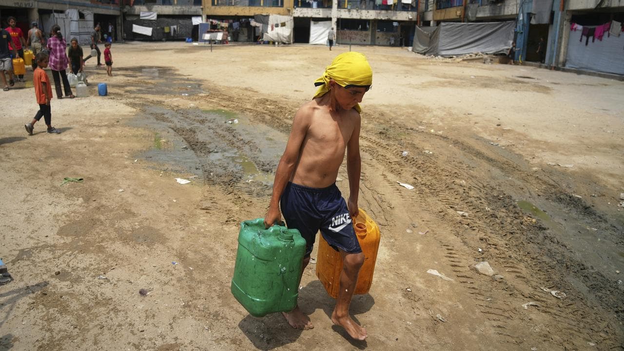 A displaced boy carries jerrycans