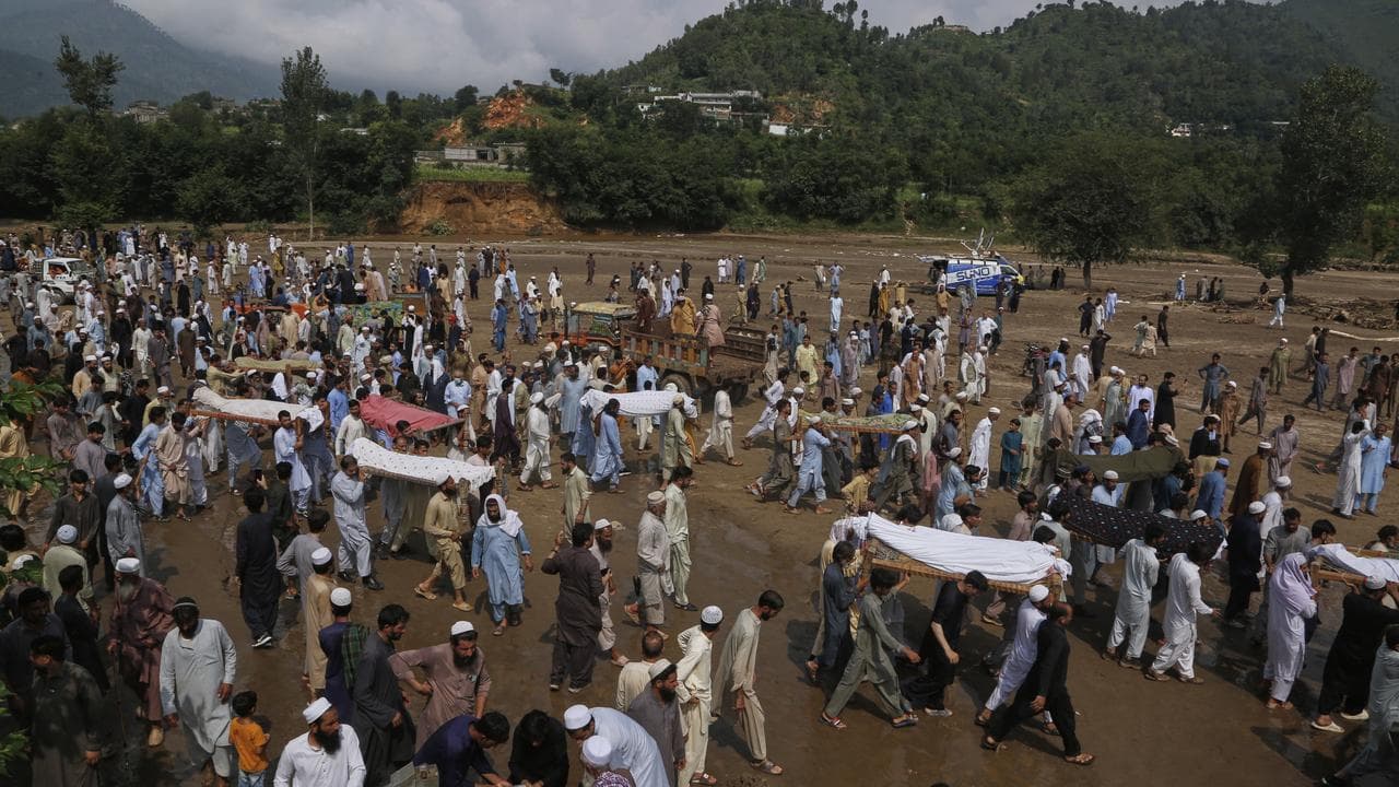 People carry bodies of the victims of flash flooding in Buner district
