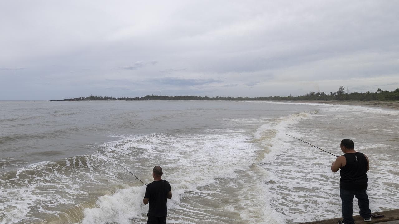 People fish along the shore in Arecibo, Puerto Rico, as Hurricane Erin