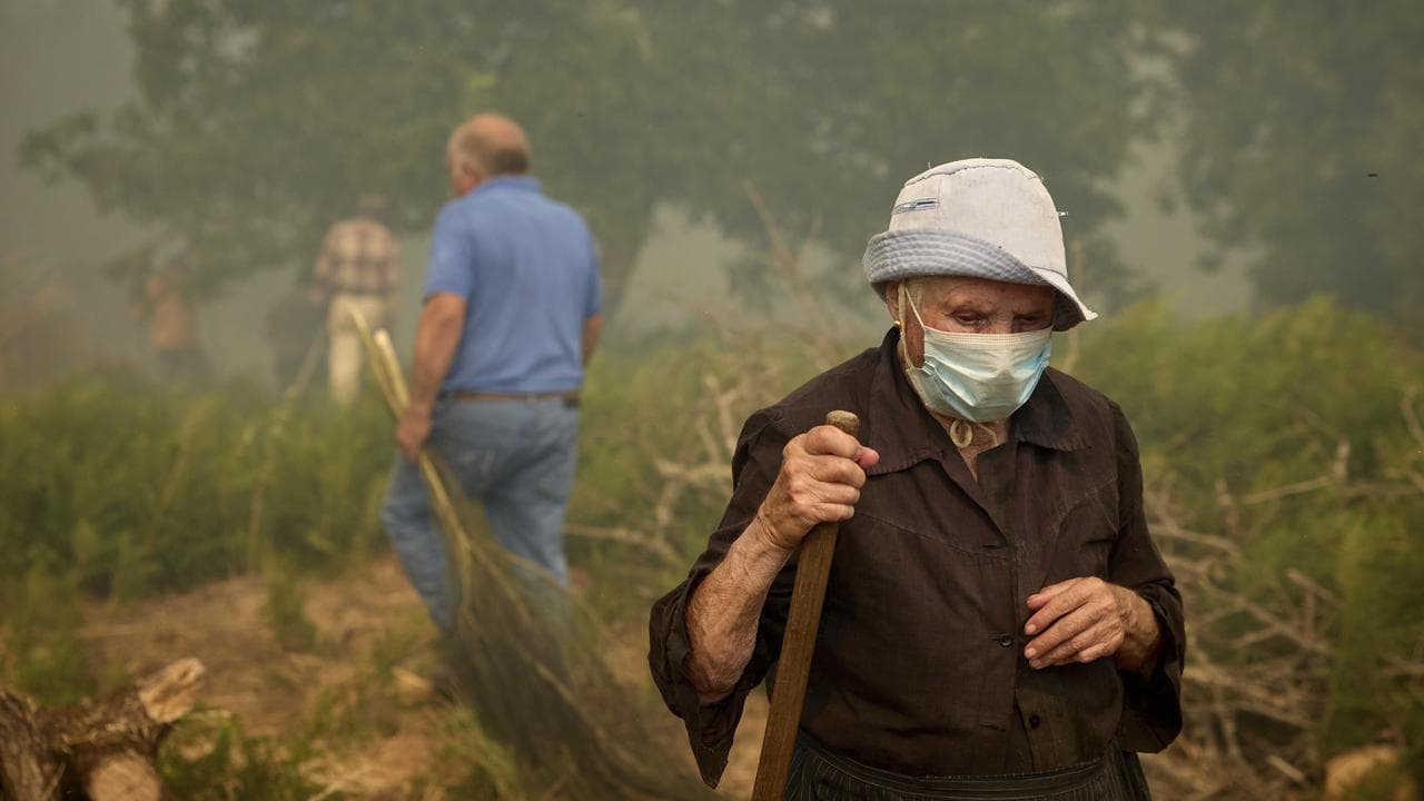 Residents walk as a fire advances near Ourense, in northwestern Spain
