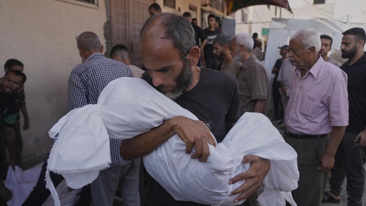 Man carries the body of his daughter after an Israeli air strike
