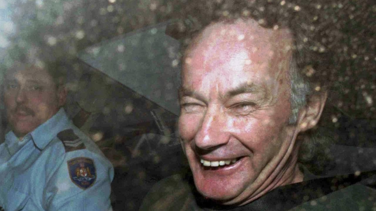 Ivan Milat smiles in a police car 