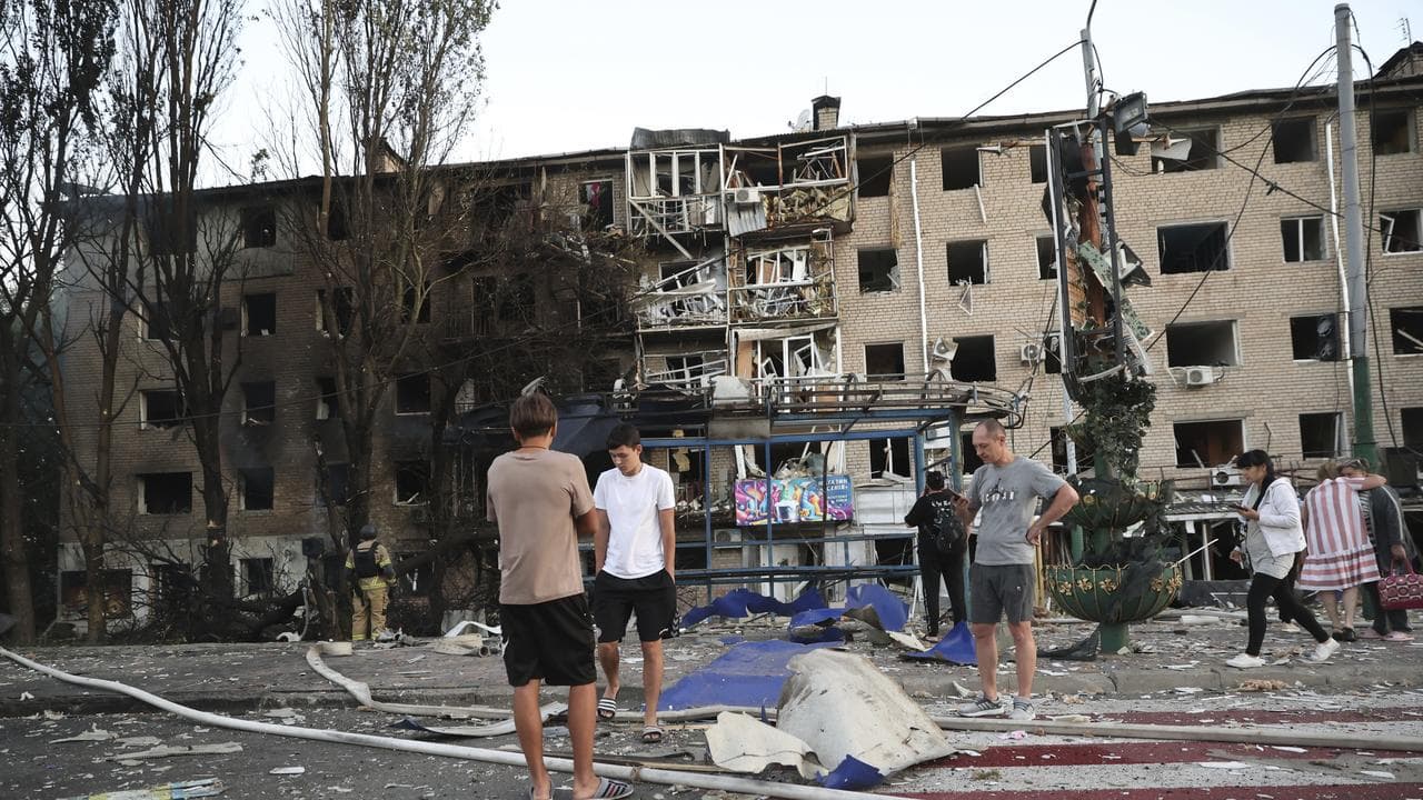 residents stand near their destroyed home in a Russian air strike