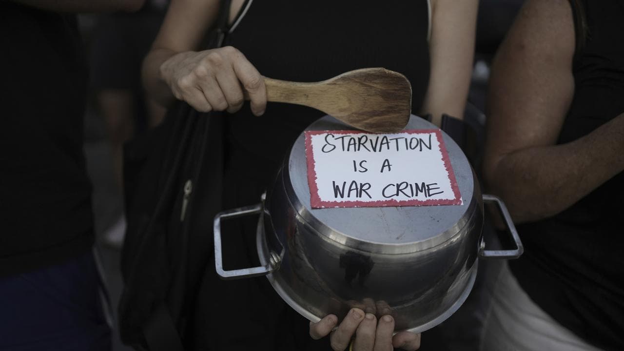 An Israeli activist bangs a pot with a wooden spoon