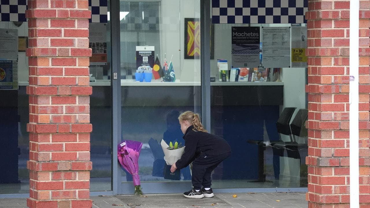 A young girl places flowers at Myrtleford Police Station (file image)